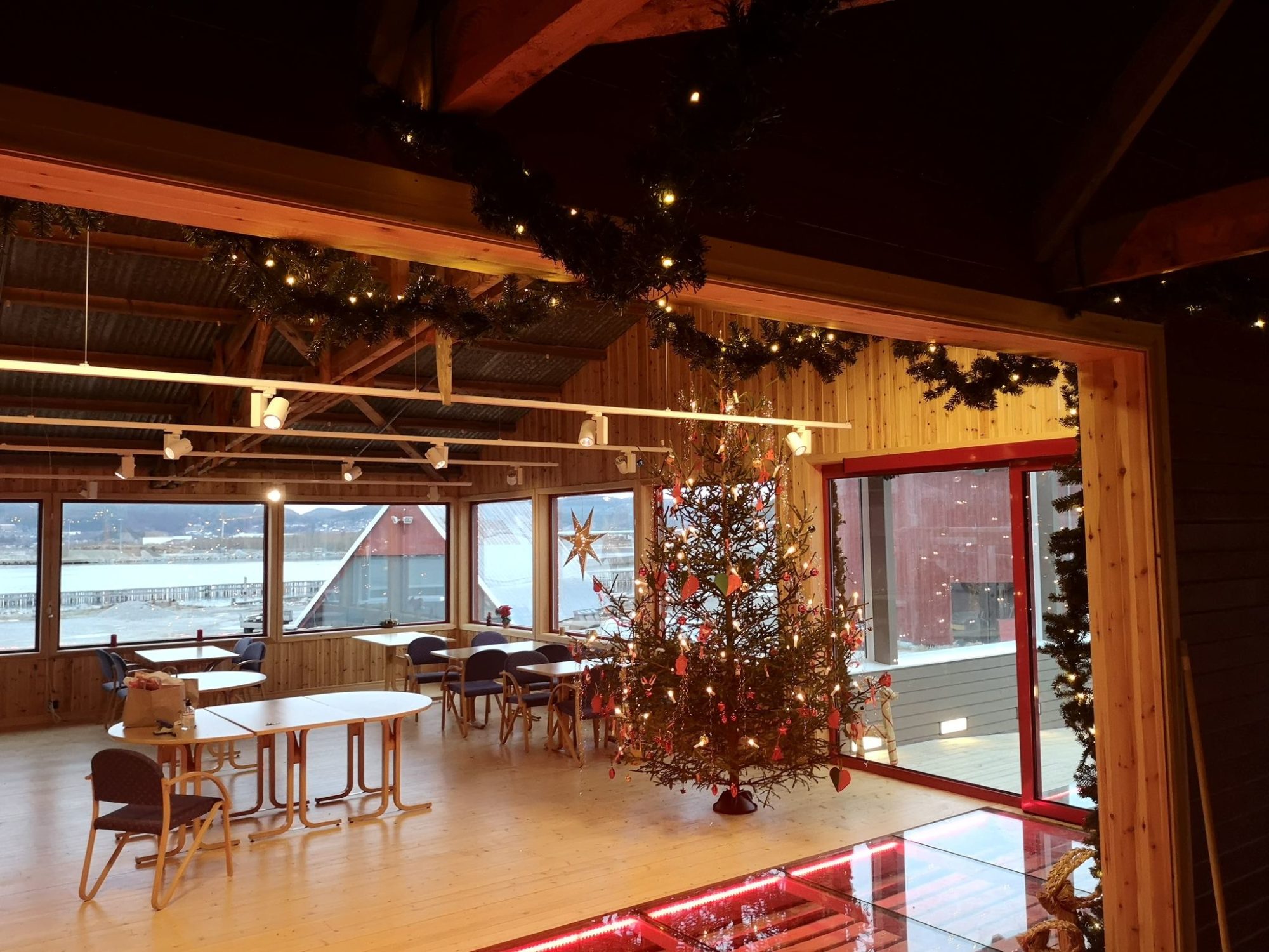 Besøkssenteret sett fra resepsjonen mot vinduene med utsikt til Namsos by. Besøkssenteret er pyntet til jul, med juletre og granbargilander.
